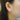 Close-up of an ear wearing a diamond stud earring with blurred background
