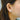 Close-up of an ear wearing a diamond earring with blurred background