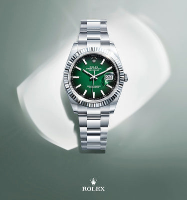 Silver Rolex Datejust watch with a green face on a gray background