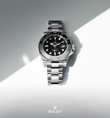 Silver watch with black face on a gray and white background, featuring the Rolex logo.