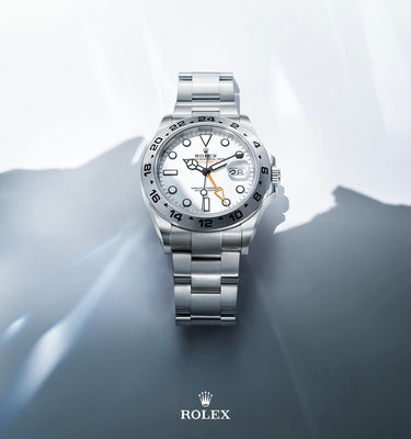 Silver Rolex watch on a gray surface with a light gray background