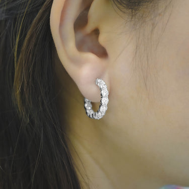 Close-up of an ear wearing a silver hoop earring with a blurred background