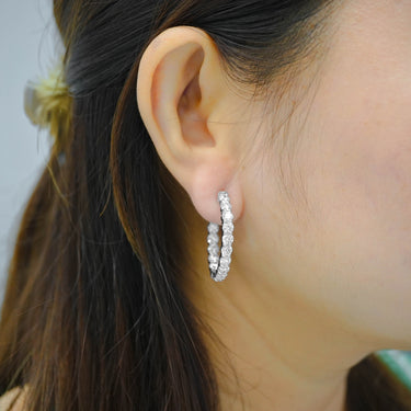 Close-up of an ear wearing a silver hoop earring with a blurred background