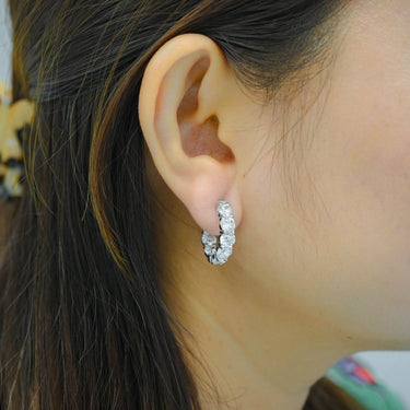 Close-up of an ear wearing a diamond hoop earring with blurred background