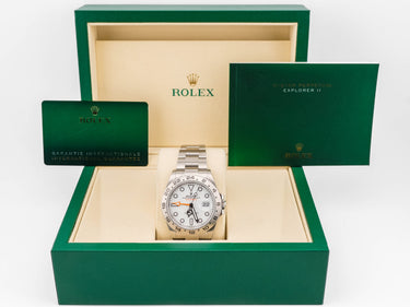 Rolex watch in a green box with a white face and gold accents.