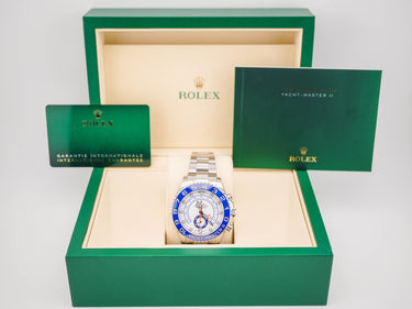 Rolex watch with green box and card on a white background