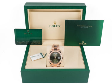 Rolex watch in a green box with accessories on a white background