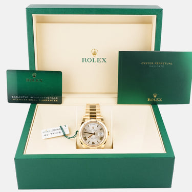 Gold watch in a green Rolex box on a white background