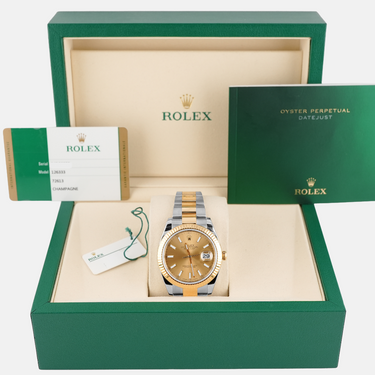 Gold watch in a green Rolex box with accessories on a white background