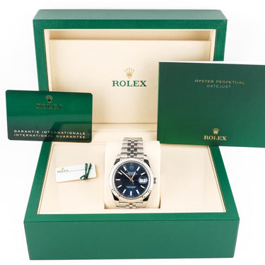 Rolex watch in a green box with accessories on a white background