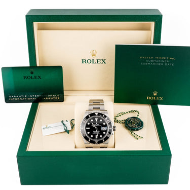 Rolex watch in a green box with warranty card on a white background