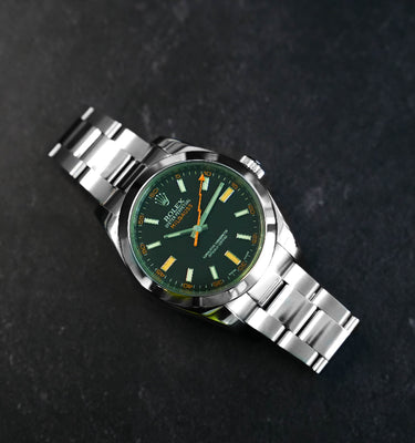 Silver watch with a green dial on a dark background