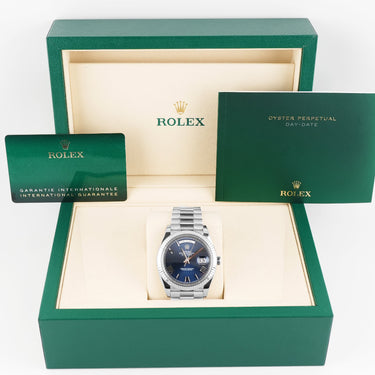 Rolex watch in a green box with accessories on a white background