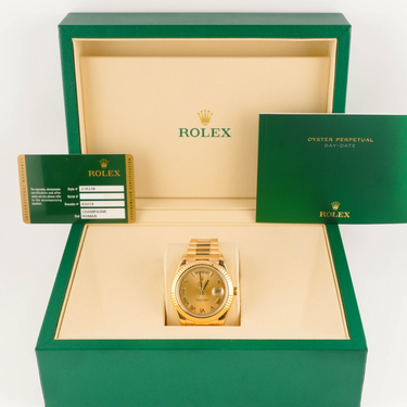 Gold Rolex watch in a green box with a white background
