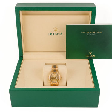 Gold Rolex watch in a green and beige box with the Rolex logo.