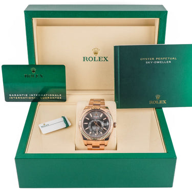 Rolex watch in an open green box with accessories on a white background