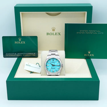 Rolex watch with blue face and silver case in green box on light blue background
