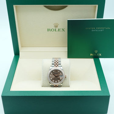 Rolex watch in an open green box on a light blue background