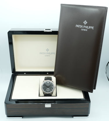 Watch in a display case with a Patek Philippe cover on a white background