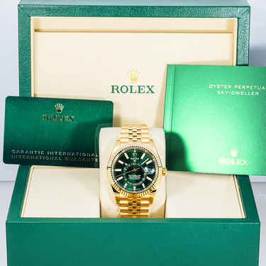Gold Rolex watch with green face in a green box with Rolex branding