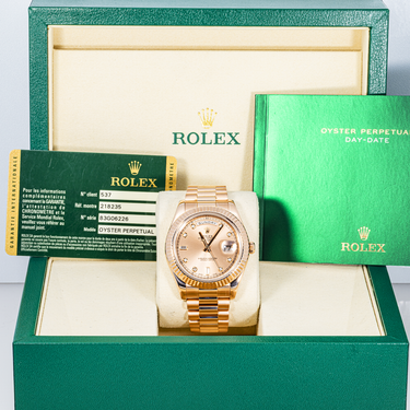 Gold Rolex watch in a green Rolex box with warranty card