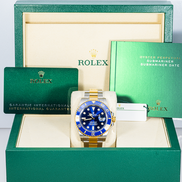 Rolex watch with blue face and gold accents in a green box
