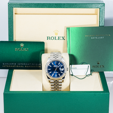Rolex watch with blue face and silver bracelet in a green Rolex box with warranty card