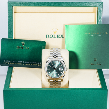 Rolex watch with green face and silver bracelet in a green box with warranty card and Rolex booklet
