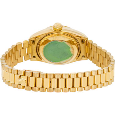 Gold wristwatch with a green face on a white background