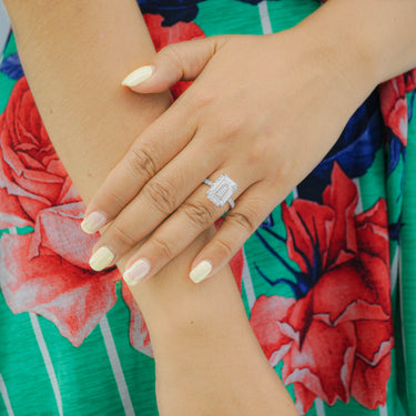 Close-up of a hand wearing a ring with a colorful floral background