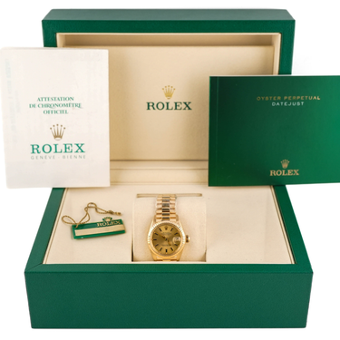 Gold Rolex watch and keychain in a green and beige box with Rolex branding.