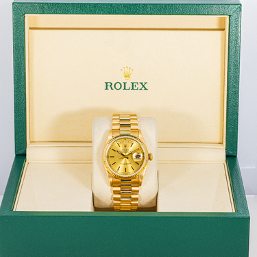 Gold Rolex watch in a green and beige box with the Rolex logo.