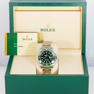Rolex watch with green face and silver case in an open green and beige box.