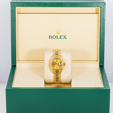 Gold Rolex watch in a green and beige box
