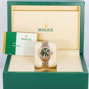 Rolex watch in an open green and beige box with the Rolex logo visible.