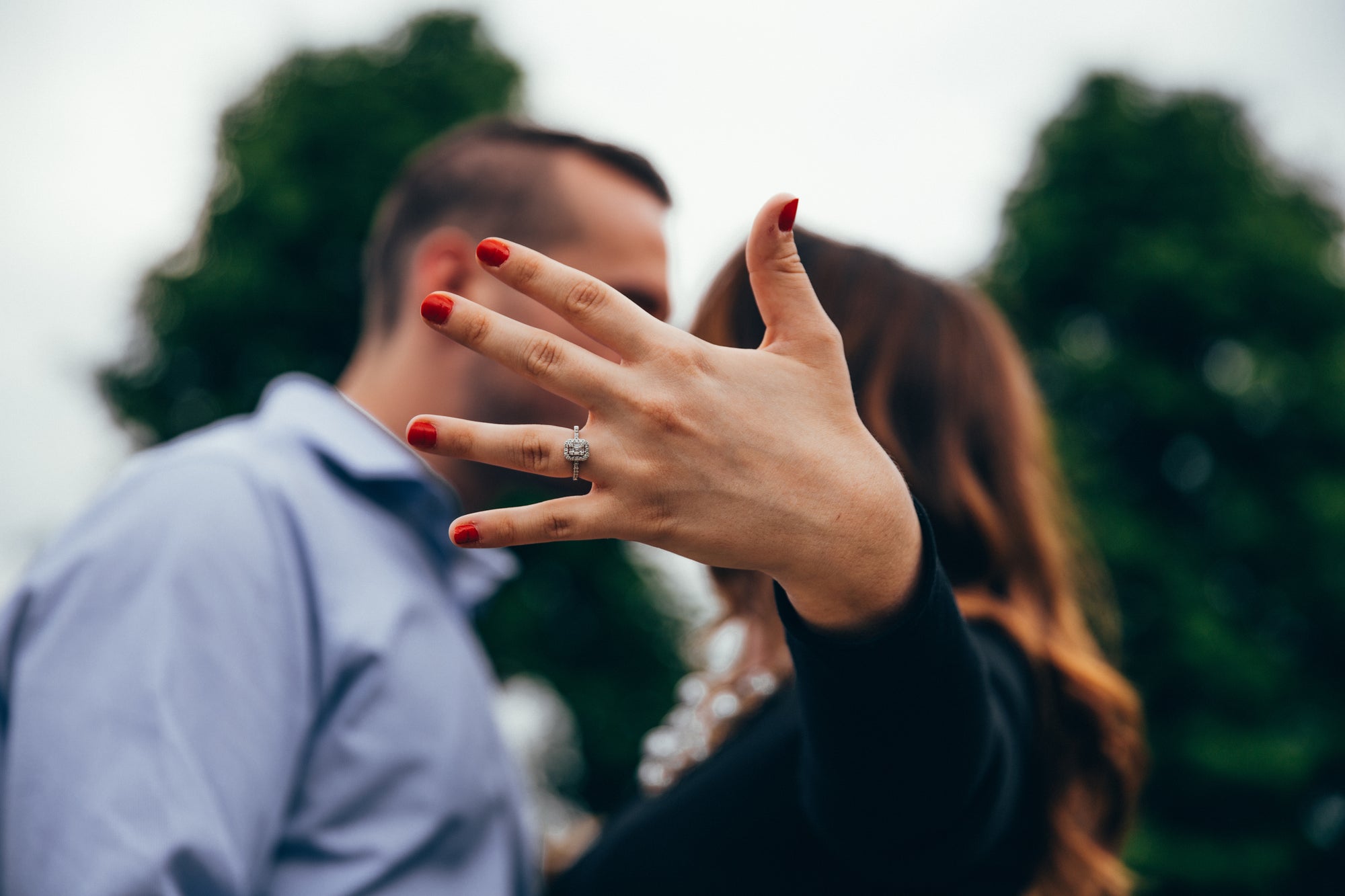 a couple showing a diamond engagement ring on a blurred background