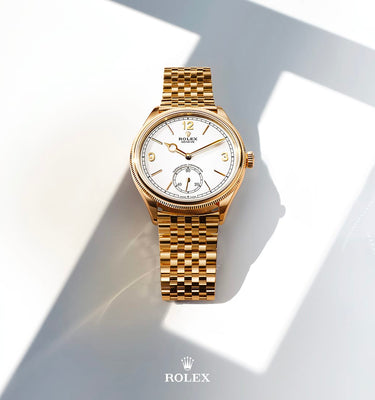 Gold watch with white face on a light gray background