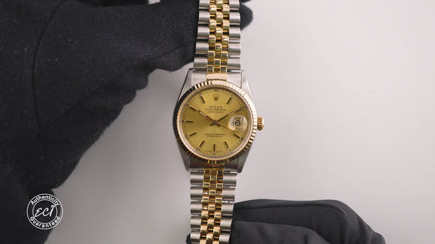 Two-tone gold and silver watch with a gold face on a white background