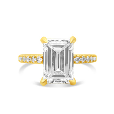 A ladies' emerald-cut diamond engagement ring with yellow gold band and smaller diamond accents along the band.